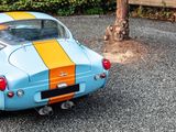 a small blue car with a yellow stripe parked in a parking lot