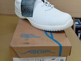 des chaussures blanches pour homme posées sur une boîte, sur une table, devant un carton