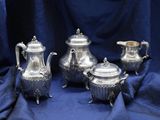 four pieces of silver tea and coffee set on a blue cloth