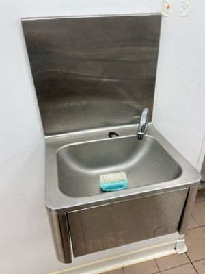 a stainless steel sink in the corner of a bathroom