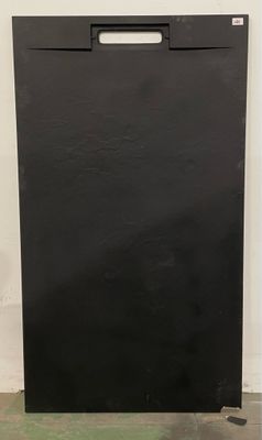 un lave-vaisselle noir posé sur un sol vert, à côté d'un mur blanc