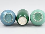 three green and blue vases sitting next to each other on a white surface
