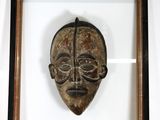 photo encadrée d'un masque en bois, dans un cadre en bois, posée sur une étagère