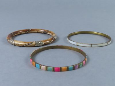 trois bracelets de couleurs différentes posés sur une surface grise