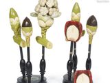 three figurines of different fruits and vegetables on display