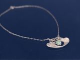 un gros plan d'un collier en argent orné d'une pierre verte