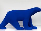un grand ours polaire bleu assis sur une surface blanche