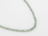 un gros plan d'un collier de perles vertes posé sur une surface blanche