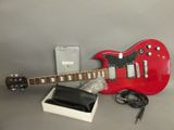 une guitare électrique rouge posée à côté d'une boîte blanche