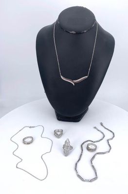 necklaces, bracelets, and rings on display on a white table