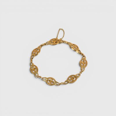 gros plan d'un bracelet en or sur fond blanc