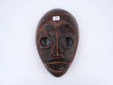 gros plan d'un masque en bois sur une surface blanche