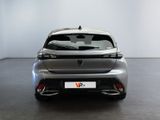 the rear end of a silver car in a room with a white wall