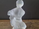 a glass figurine of a woman sitting on a table