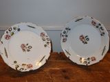 two plates with floral designs on them sitting on a wooden table
