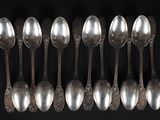 six cuillères en argent sont alignées sur un fond noir