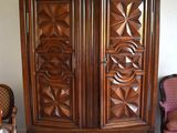 a wooden armoire in a room with a chair and a table