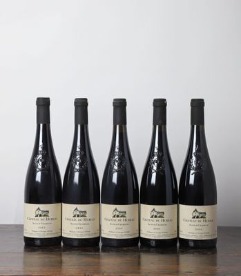 cinq bouteilles de vin sont posées sur une table devant un mur blanc