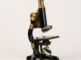 un gros plan d'un microscope noir et doré sur fond blanc