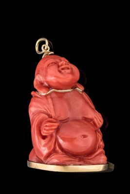 statue d'un Bouddha rouge souriant posée sur un socle plaqué or, sur fond noir