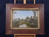 une peinture à l'huile représentant une rivière et des arbres, dans un cadre en bois