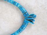 turquoise howlite beads are arranged in a spiral shape on a white surface