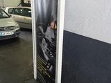 des voitures garées dans un parking couvert, avec une affiche sur le côté du bâtiment