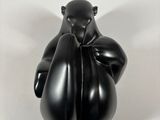 black sculpture of a bear sitting on top of a white surface