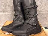 pair of black motorcycle boots sitting on top of a cardboard box