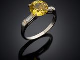 a close up of a yellow sapphire and diamond ring on a black surface