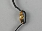 a close up of a black cord with a gold ring on it