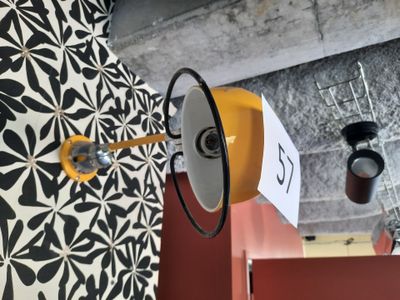 une lampe jaune fixée au mur, à côté d'un mur noir et blanc