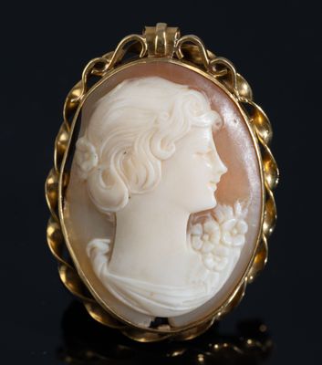 un camée ancien sculpté dans un coquillage, représentant une femme avec des fleurs dans les cheveux