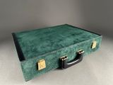 a green suitcase sitting on a table with a black handle