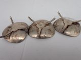three silver plated spoons sitting on top of a white table
