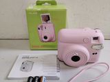 a pink camera sitting next to a box of batteries
