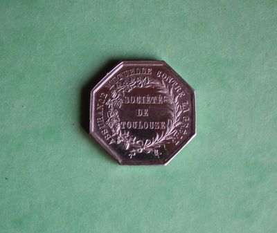 a silver coin on a green surface with a picture on it
