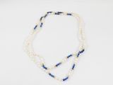 un collier de perles blanches et bleues posé sur un fond blanc