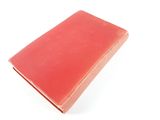 an old red book sitting on top of a white surface