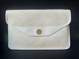 un sac à main blanc orné d'un bouton doré sur le devant