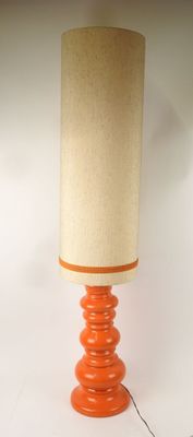 an orange table lamp with a beige shade on top of it