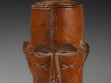 un vieux masque en bois représentant un visage, posé sur un socle