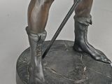 bronze statue of a man with a sword and hat on a base
