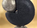 a sculpture of a black and silver object on top of a marble block
