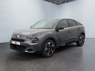 Une voiture grise est garée dans une grande pièce au sol noir.