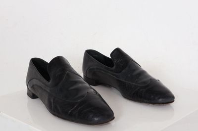 paire de chaussures en cuir noir sur une surface blanche avec un fond blanc