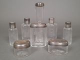five glass jars with silver lids on a table