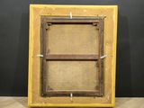 an old picture frame sitting on top of a wooden floor next to a black wall