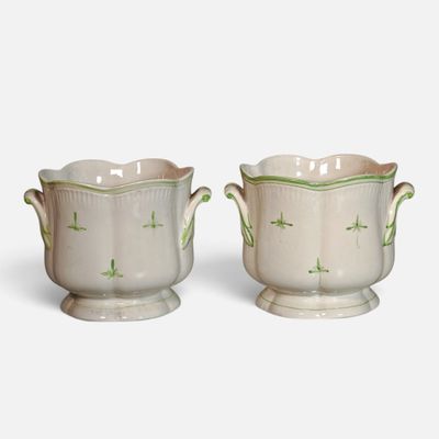 two white vases with green designs on them sitting next to each other
