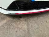 the front bumper of a white car with a red stripe
